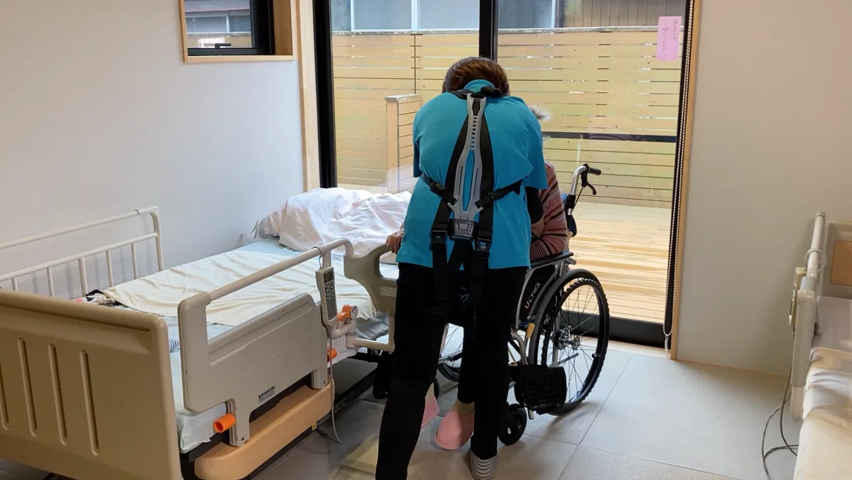 Profesional sanitario utilizando un exoesqueleto ocupacional durante una tarea clínica de movilización de pacientes en un entorno hospitalario